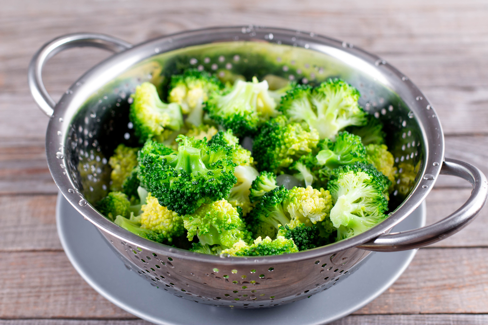 Blanched broccoli in a stainless steel colander