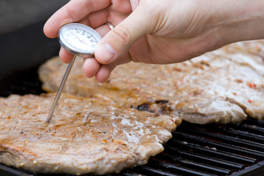 checking the grilled beef’s temperature using a cooking tool